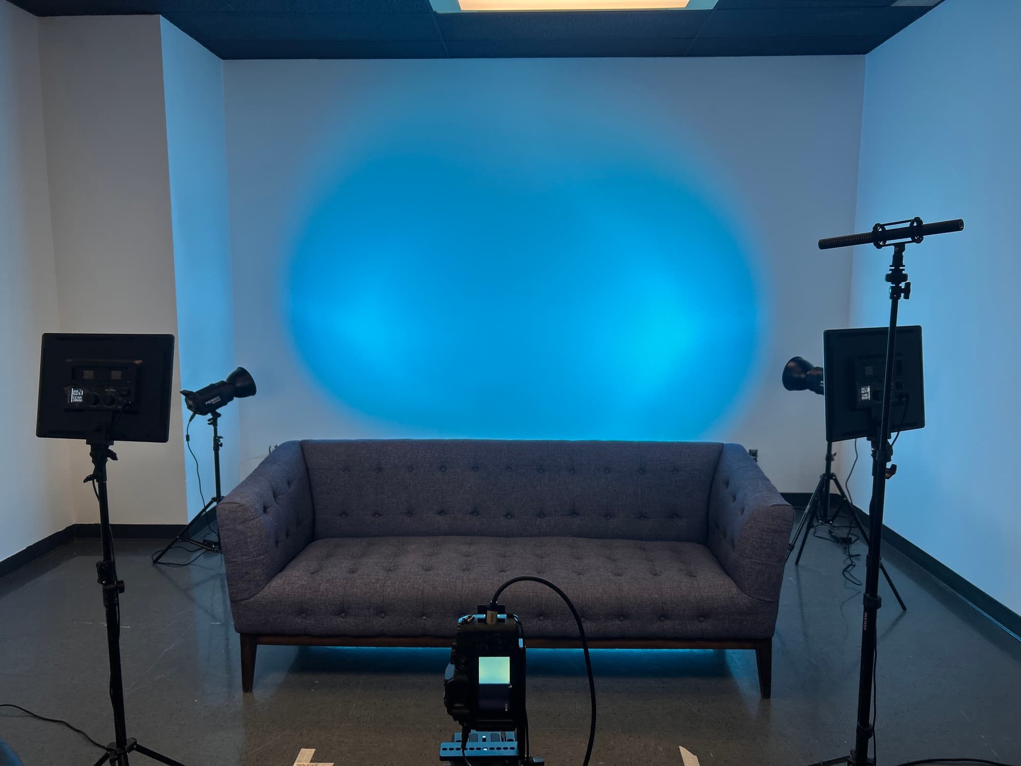 Décor divan gris et éclairage bleu du Studio de l'île, prêt pour un tournage